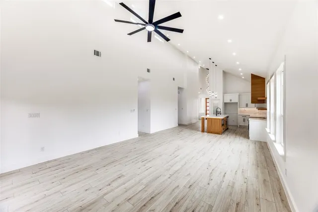 a large living room with stainless steel appliances furniture wooden floor and a large window