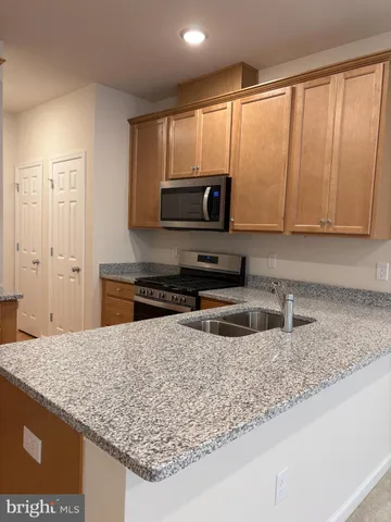 a living room with stainless steel appliances kitchen island granite countertop a refrigerator sink and cabinets