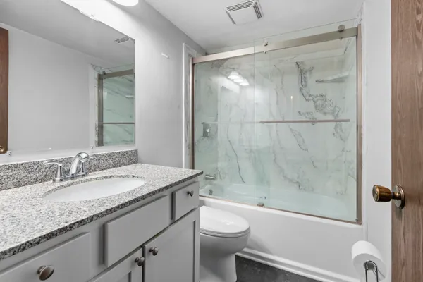 a bathroom with a granite countertop sink toilet and shower