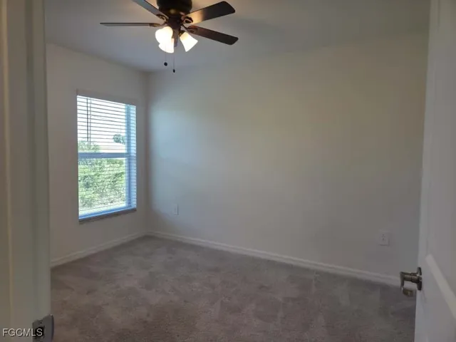 an empty room with a window and a fan