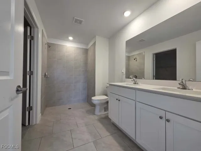 a bathroom with a double vanity sink toilet and a mirror