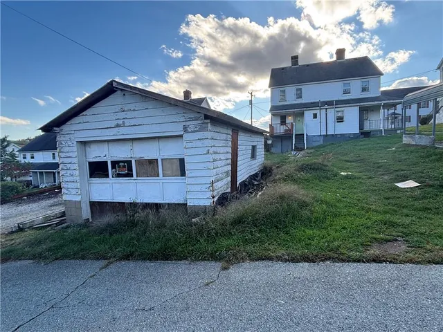 a view of a brick house next to a yard with potted plants