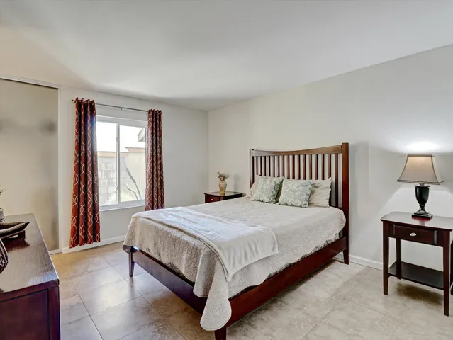 a large bed sitting in a bedroom next to a window with a lamp and a dresser