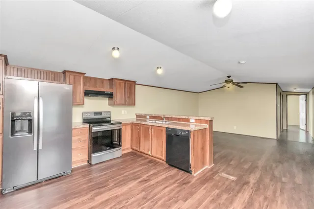 a kitchen with stainless steel appliances a refrigerator a sink and wooden floors