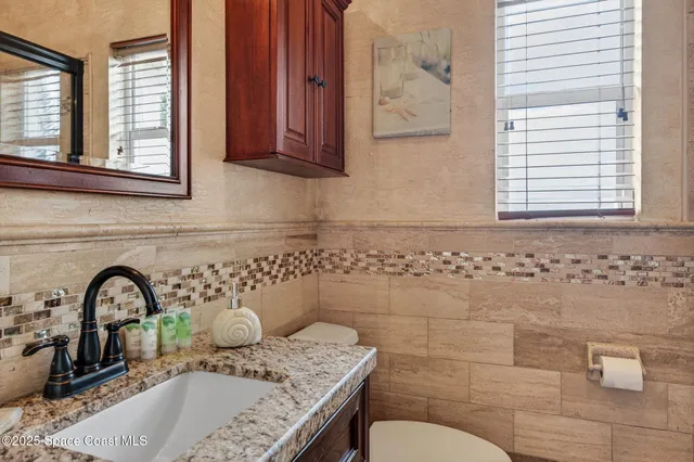 a bathroom with a granite countertop sink a toilet and mirror