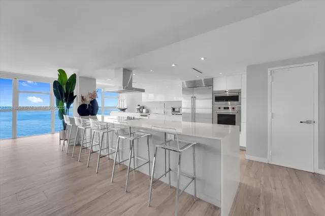 a kitchen with stainless steel appliances kitchen island wooden floors and white cabinets