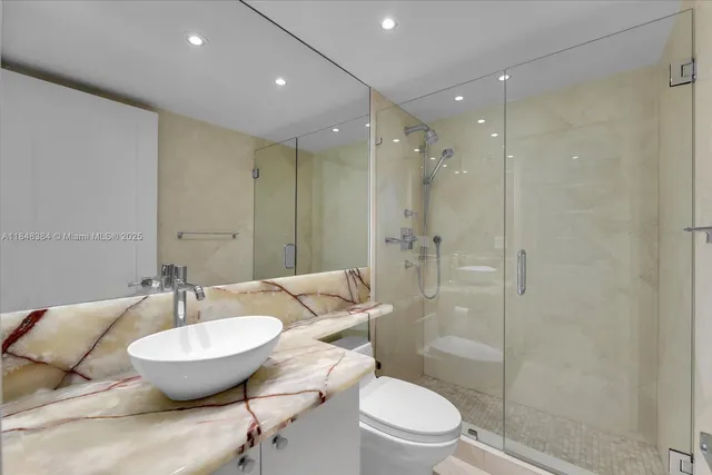 a bathroom with a granite countertop sink a toilet a mirror and shower