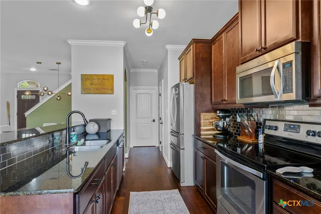 a kitchen with stainless steel appliances granite countertop a stove refrigerator and a microwave