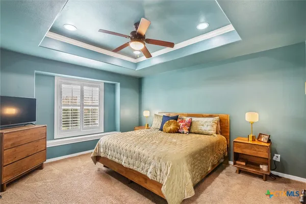 a bedroom with a bed and a flat tv screen on dresser
