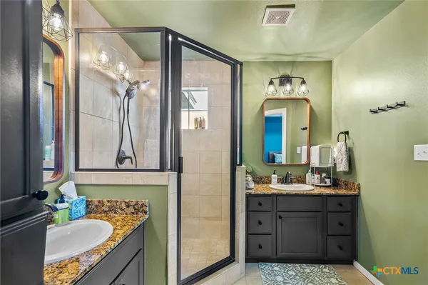 a bathroom with a sink vanity granite tub and a mirror