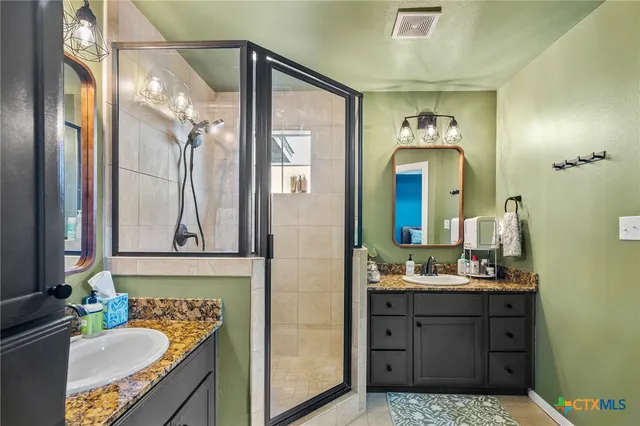 a bathroom with a sink vanity granite tub and a mirror