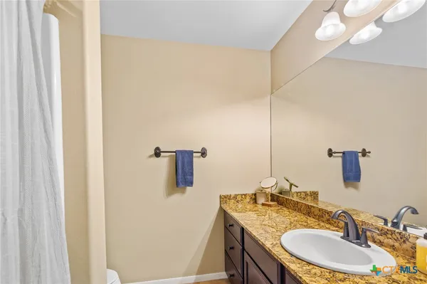 a bathroom with a granite countertop sink a mirror and shower curtain