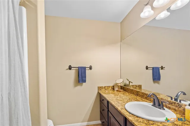 a bathroom with a granite countertop sink a mirror and shower curtain