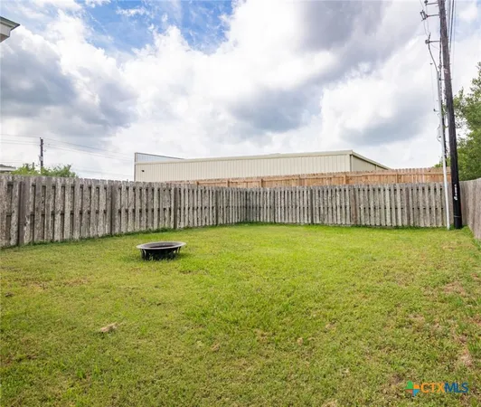 a view of a yard with wooden fence