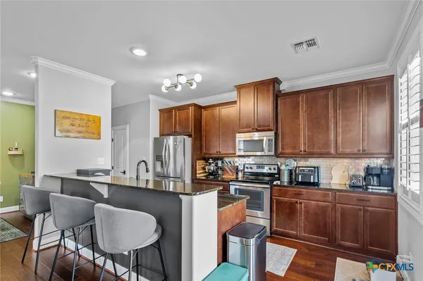 a kitchen with granite countertop a sink cabinets and stainless steel appliances