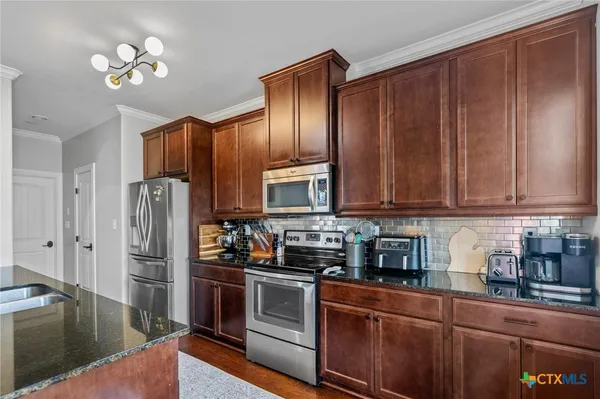 a kitchen with stainless steel appliances granite countertop a refrigerator a stove and a sink with wooden floor