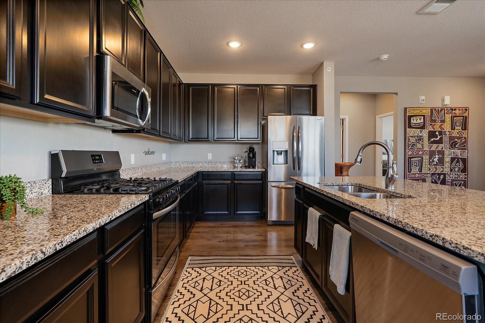 4474 Copeland Circle, Unit 203 Highlands Ranch, CO 80126 - Photo 12 of 33 a kitchen with stainless steel appliances granite countertop a stove a sink and a refrigerator
