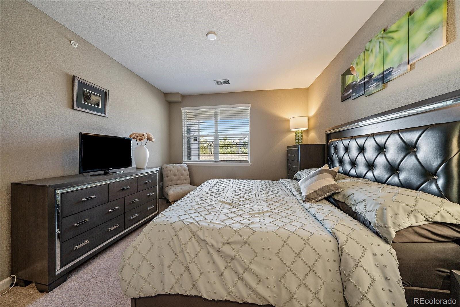 4474 Copeland Circle, Unit 203 Highlands Ranch, CO 80126 - Photo 15 of 33 a bedroom with a large bed and a flat screen tv