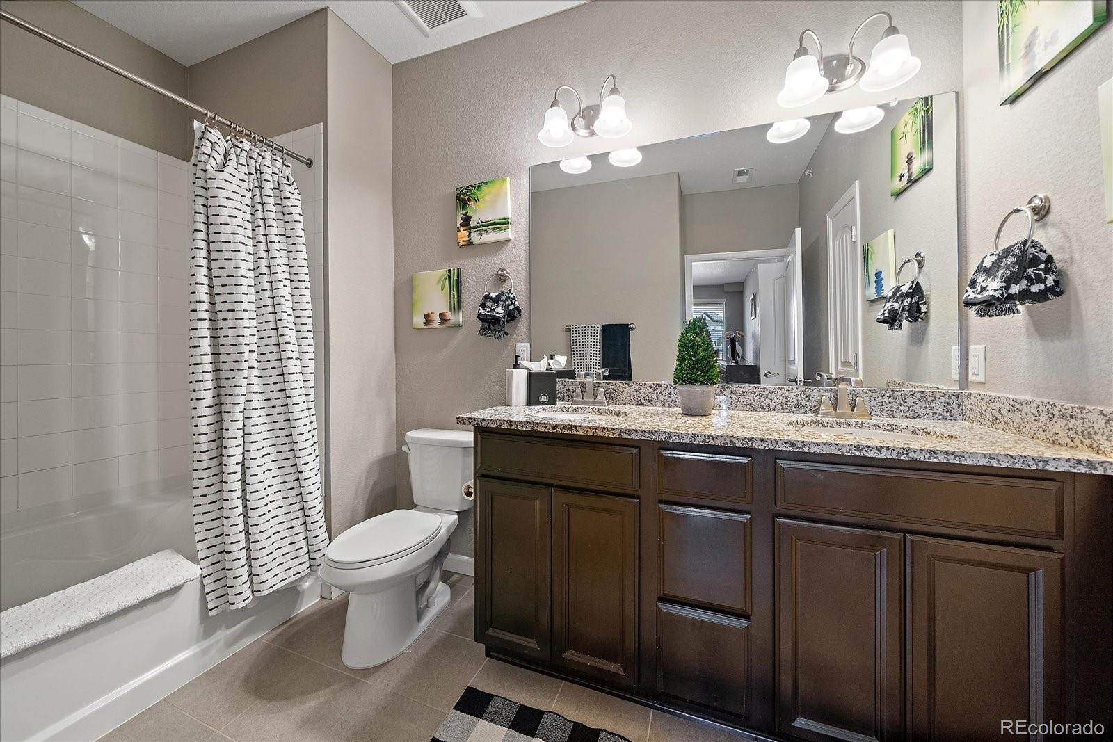 4474 Copeland Circle, Unit 203 Highlands Ranch, CO 80126 - Photo 17 of 33 a bathroom with a granite countertop sink a toilet a mirror a vanity and shower