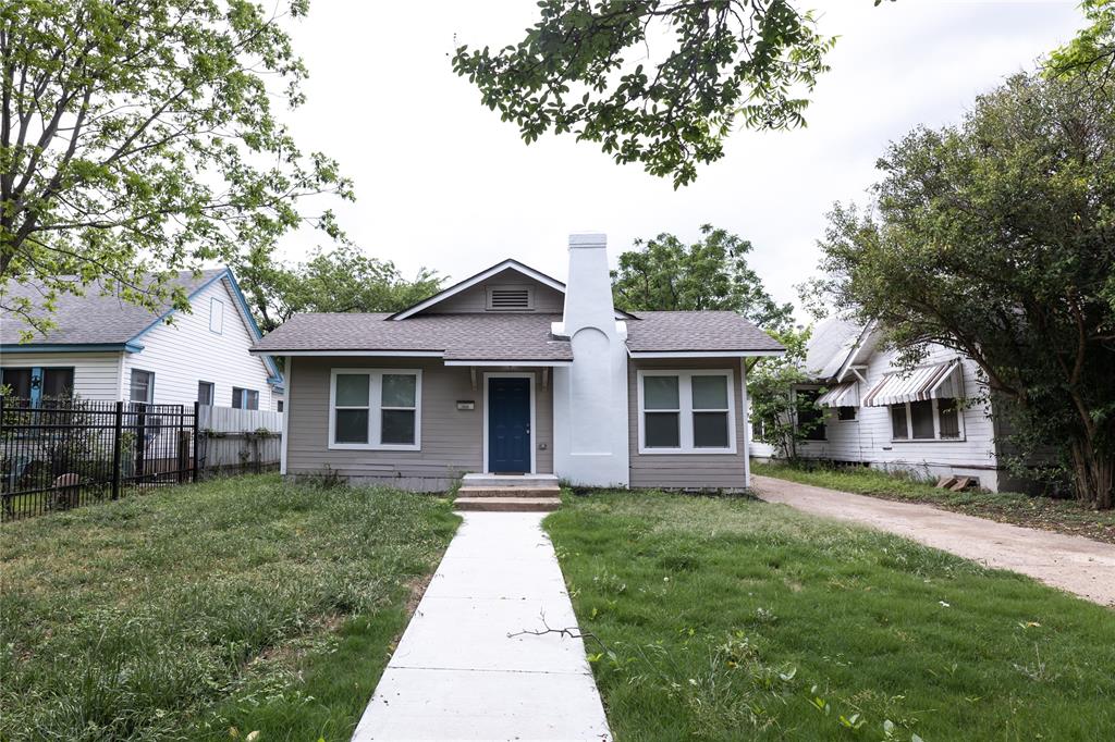 a front view of a house with a yard and potted plants