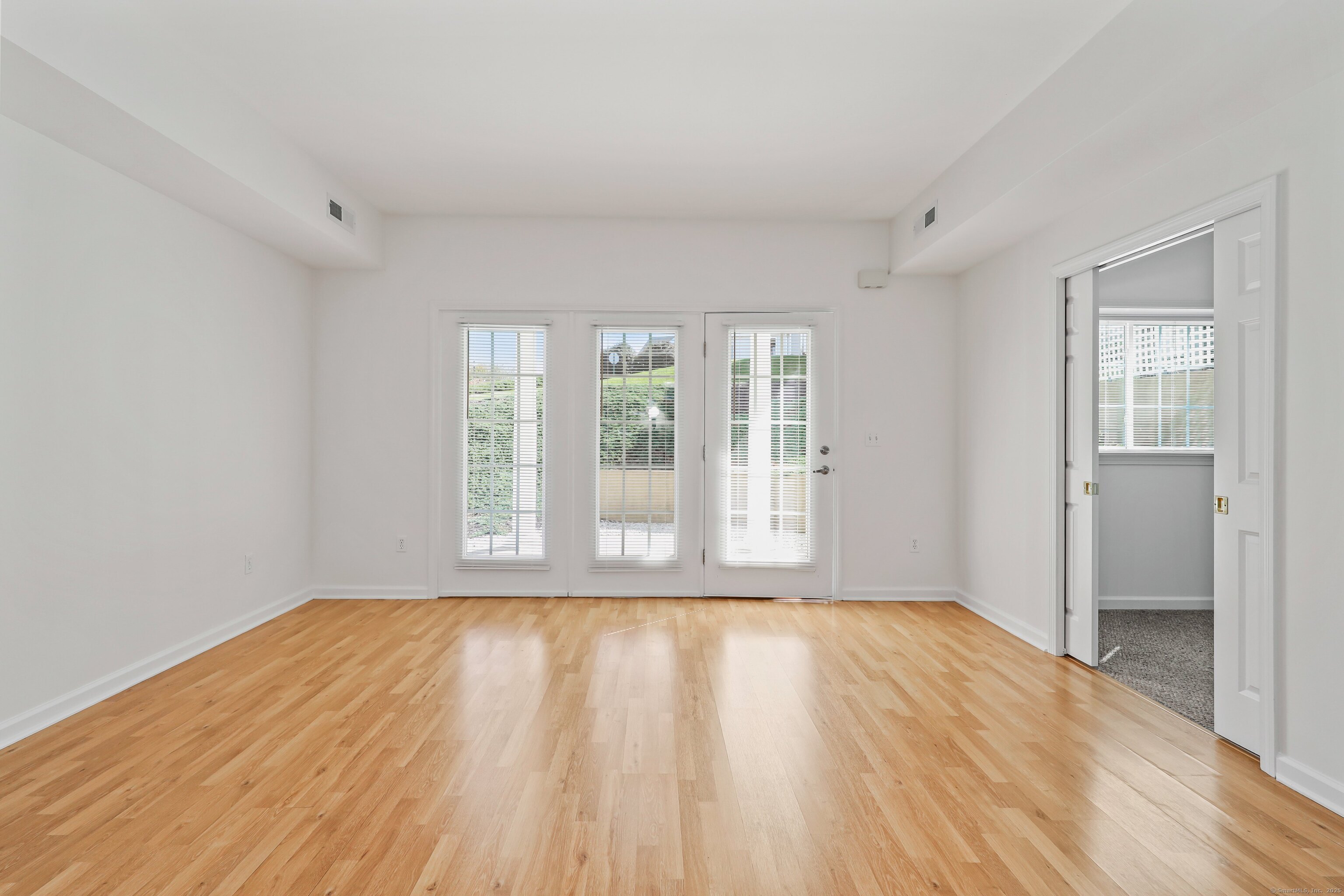 211 Pine Hill Boulevard, Unit 211 Plymouth, CT 06782 - Photo 11 of 35 a view of an empty room with wooden floor and a window