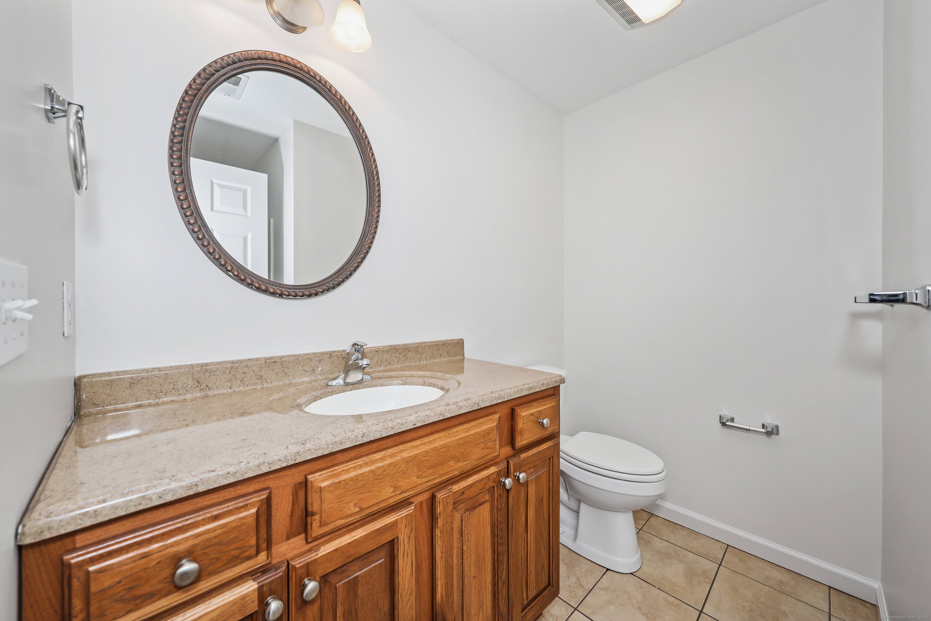 211 Pine Hill Boulevard, Unit 211 Plymouth, CT 06782 - Photo 12 of 35 a bathroom with a granite countertop toilet a sink and a mirror