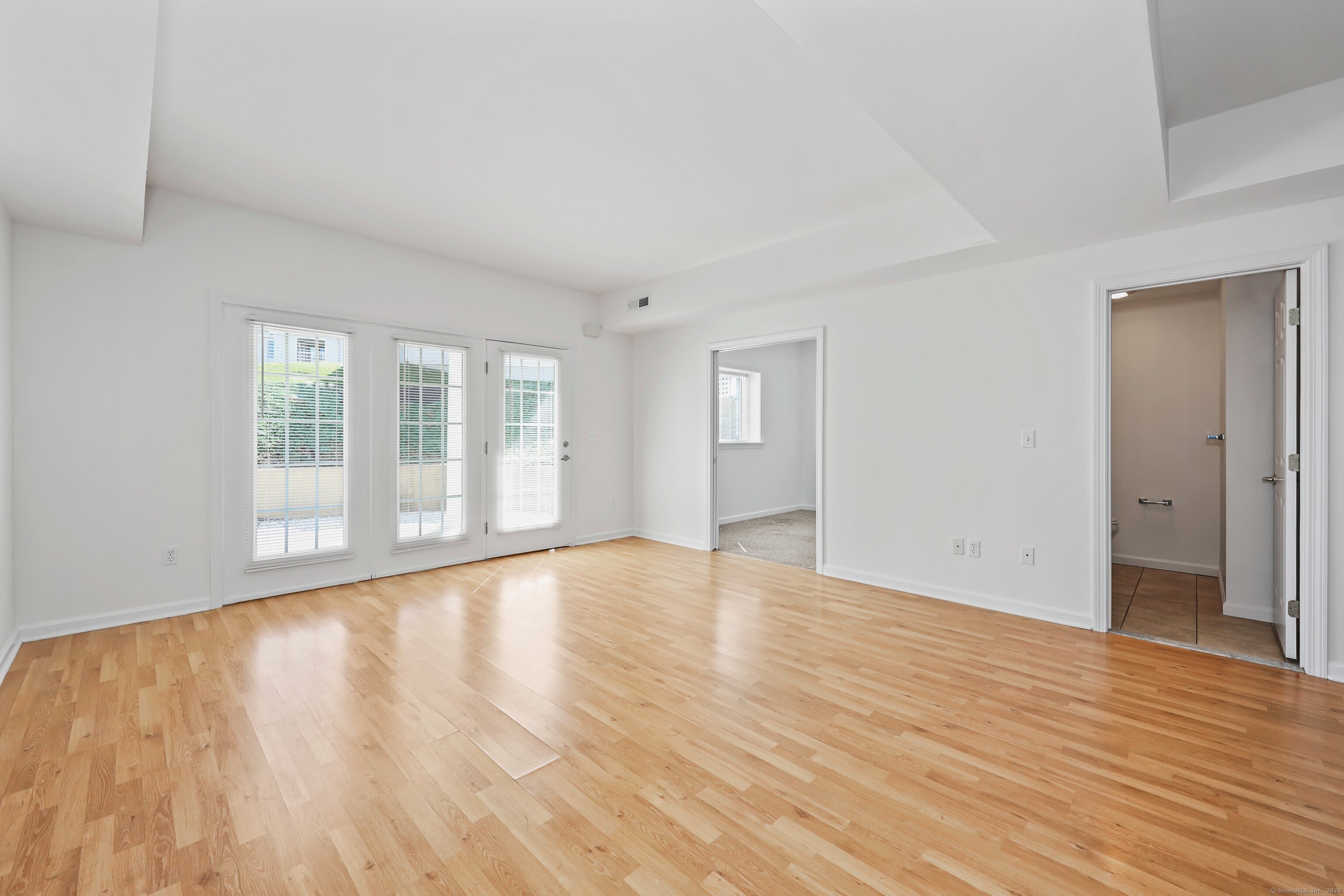 211 Pine Hill Boulevard, Unit 211 Plymouth, CT 06782 - Photo 4 of 35 a view of an empty room with wooden floor and a window