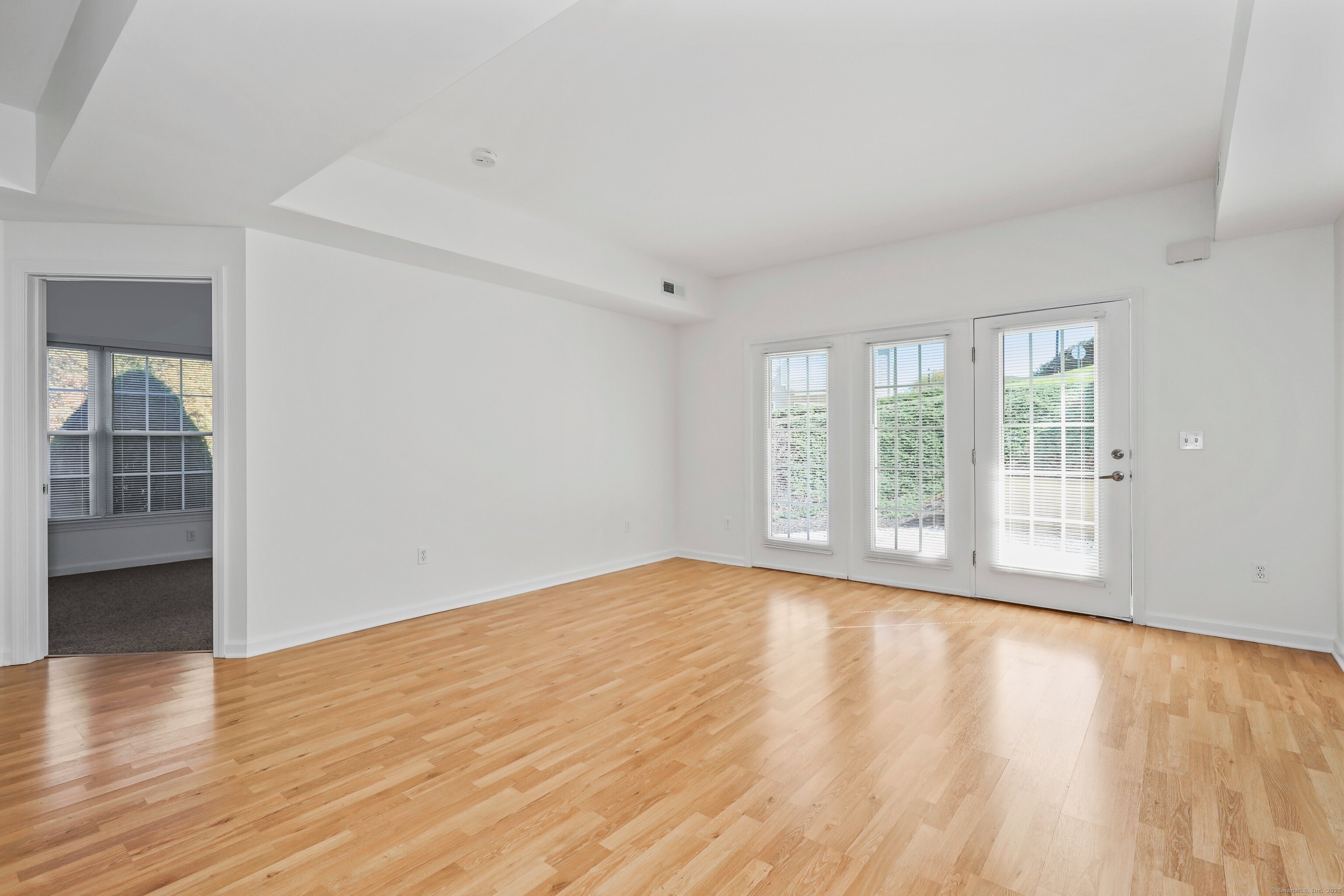 211 Pine Hill Boulevard, Unit 211 Plymouth, CT 06782 - Photo 5 of 35 a view of an empty room with wooden floor and a window