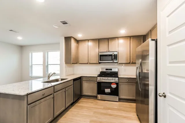 a kitchen with stainless steel appliances granite countertop a sink stove microwave and refrigerator
