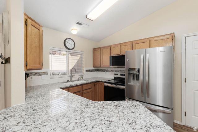 161 West 950 South, Unit S4 St. George, UT 84770 - Photo 9 of 21 Kitchen featuring stainless steel appliances, backsplash, vaulted ceiling, light stone counters, and wood finish cabinets