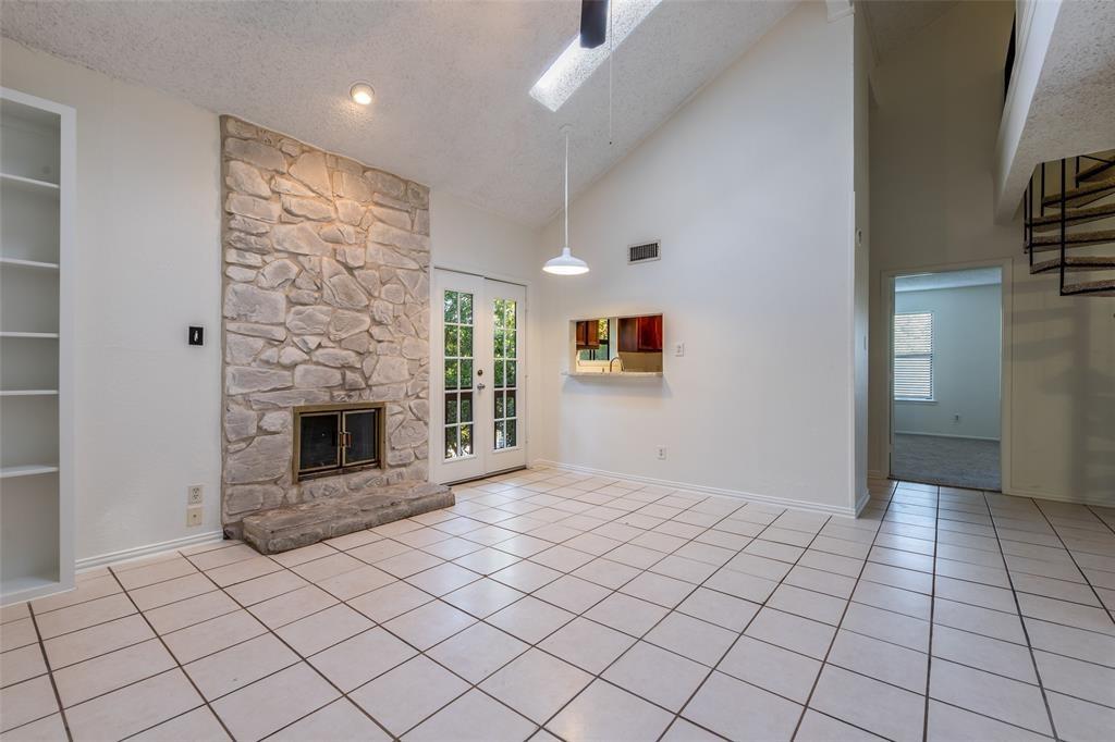 3506 Speedway, Unit 302 Austin, TX 78705 - Photo 2 of 27 Unfurnished living room with a high textured ceiling, a ceiling fan, a stone fireplace, light tile patterned floors, and a skylight