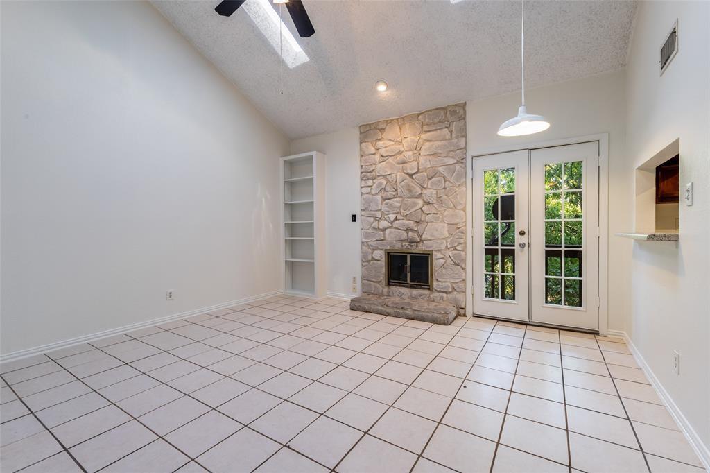 3506 Speedway, Unit 302 Austin, TX 78705 - Photo 3 of 27 Unfurnished living room with a high textured ceiling, french doors, a skylight, a stone fireplace, and light tile patterned flooring