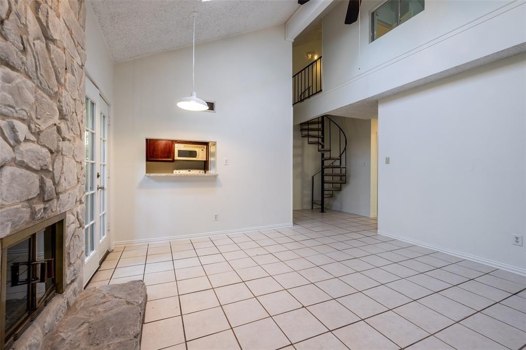 3506 Speedway, Unit 302 Austin, TX 78705 - Photo 4 of 27 Unfurnished living room featuring a stone fireplace, light tile patterned flooring, and a high textured ceiling