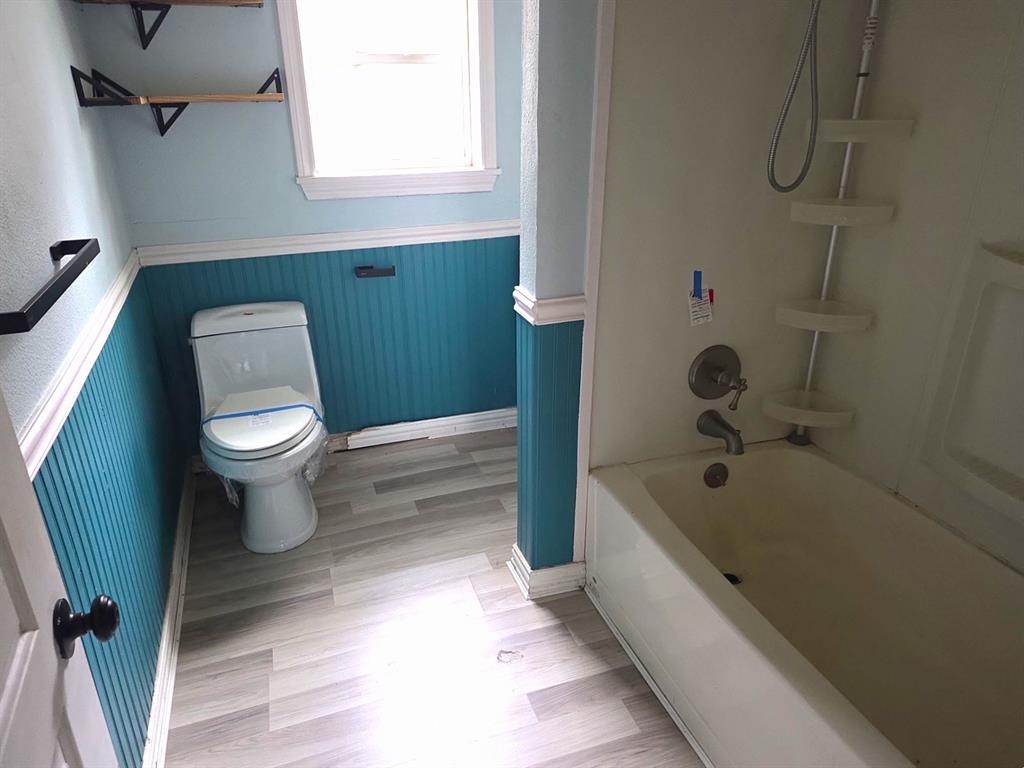 612 North Adelaide Street Terrell, TX 75160 - Photo 11 of 11 Bathroom featuring a wainscoted wall, bathing tub / shower combination, and light wood-style floors