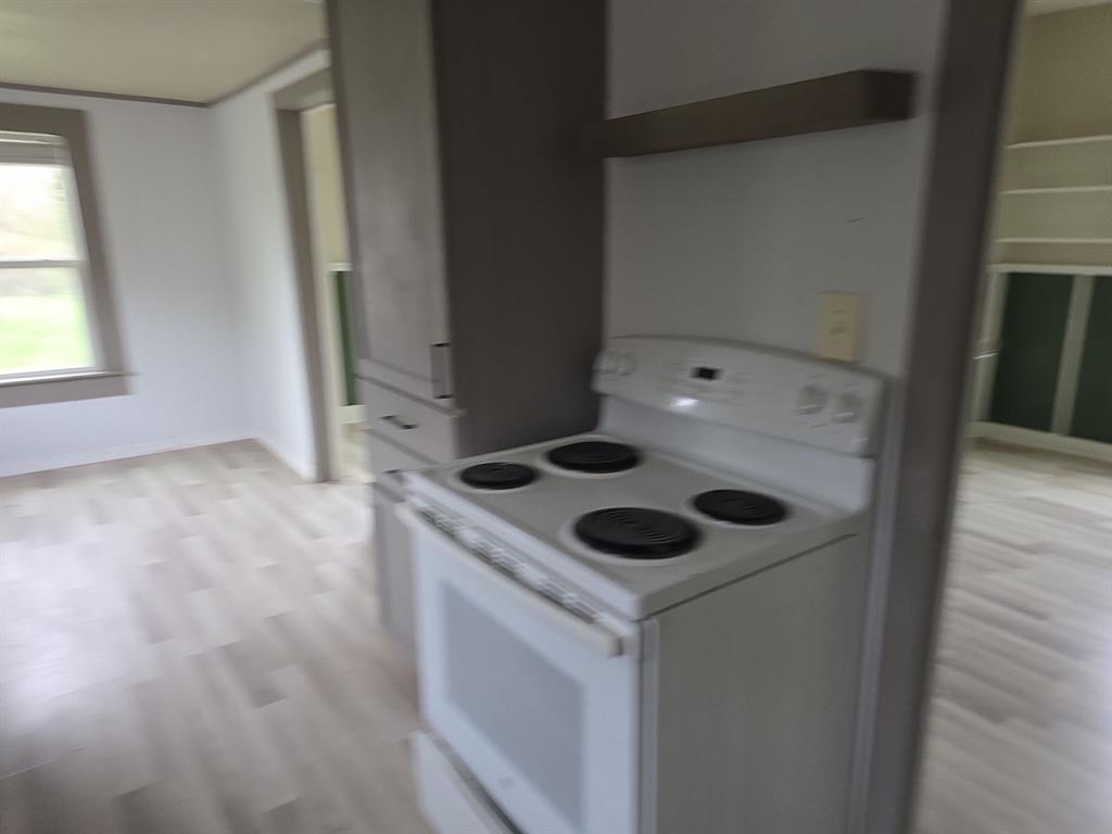 612 North Adelaide Street Terrell, TX 75160 - Photo 6 of 11 Kitchen with white range with electric cooktop, light countertops, light wood-style floors, and white cabinets