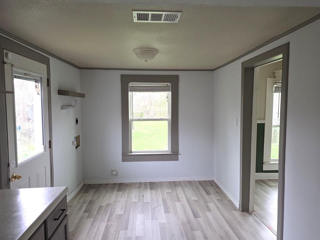 612 North Adelaide Street Terrell, TX 75160 - Photo 7 of 11 Laundry room off kitchen featuring light wood-type flooring, a textured ceiling, and ornamental molding