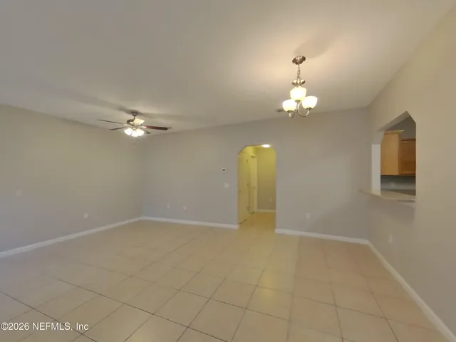 an empty room with a chandelier fan and glass door