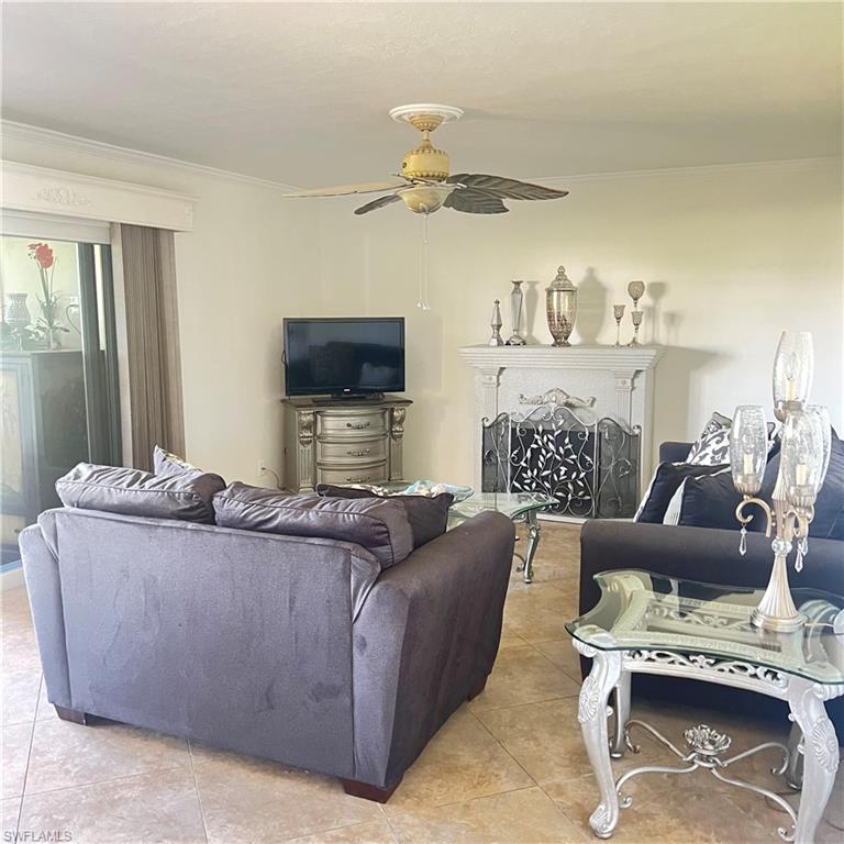 197 Harrison Road, Unit 3 Naples, FL 34112 - Photo 4 of 14 Living room with crown molding, a fireplace, light tile patterned floors, and ceiling fan