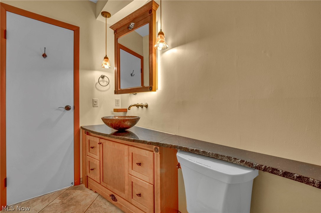 6845 Liberty Road Solon, OH 44139 - Photo 21 of 47 Wood-finish vanity with a vessel sink, dark countertop, and sconce lighting