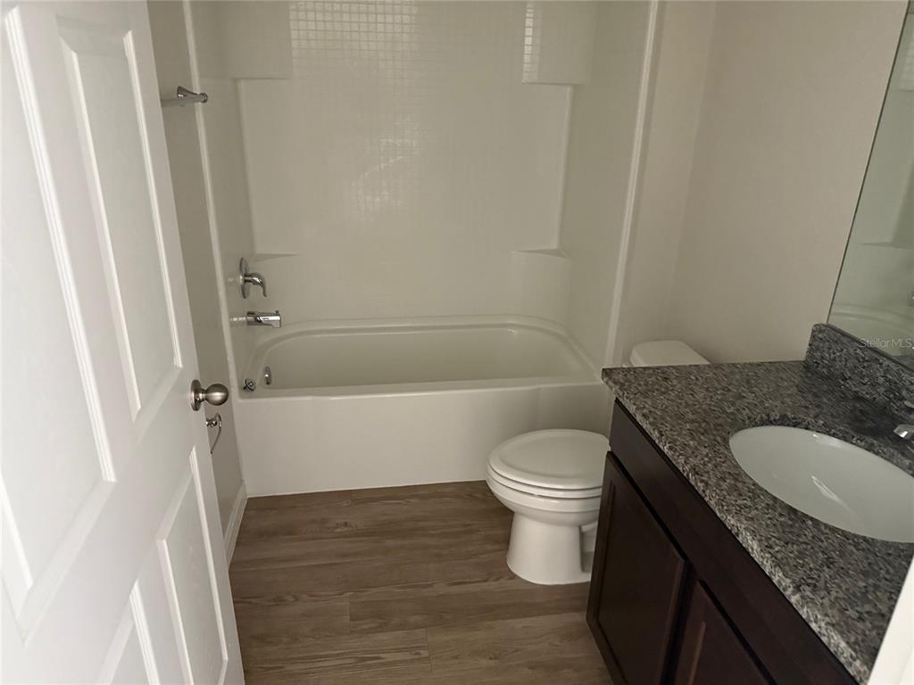 316 Pleasant Grove Road, Unit 2 Inverness, FL 34452 - Photo 9 of 12 a bathroom with a granite countertop toilet a sink and a bathtub
