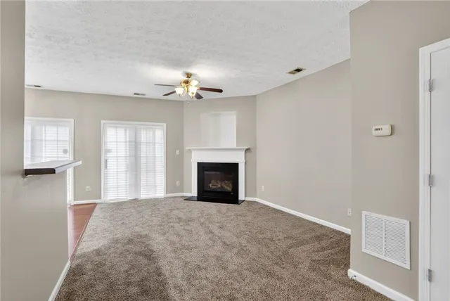 a view of an empty room with chandelier fan and fire place