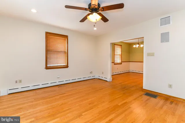 a view of empty room with wooden floor and fan