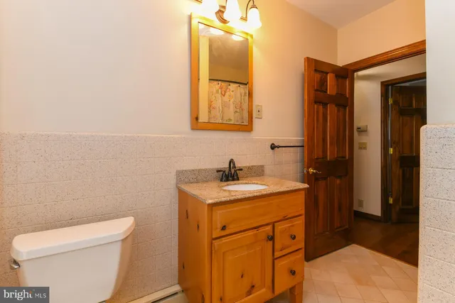 a bathroom with a granite countertop toilet a sink and a window