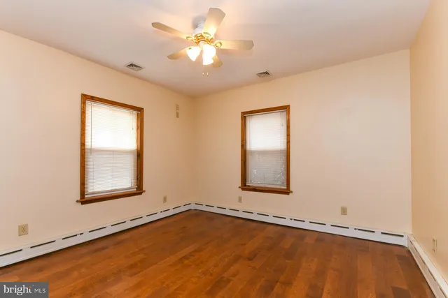 a view of an empty room with a window and wooden floor