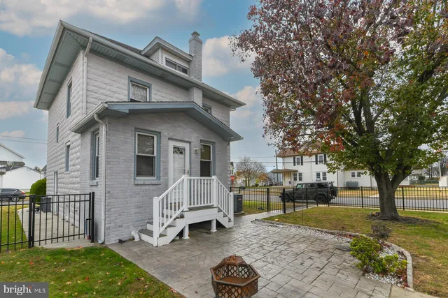a view of a white house next to a yard with big trees