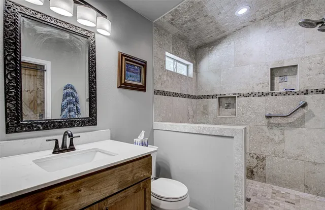 a bathroom with a granite countertop sink mirror vanity and toilet