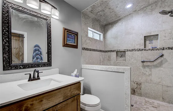 a bathroom with a granite countertop sink mirror vanity and toilet