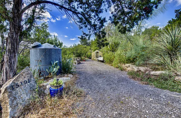 a view of a backyard with table and chairs potted plants and large tree