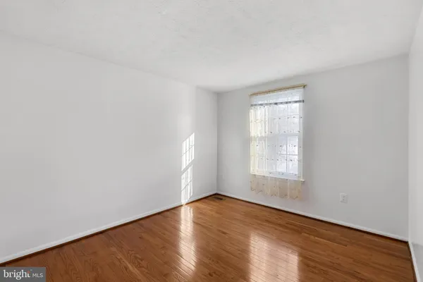 an empty room with wooden floor and window