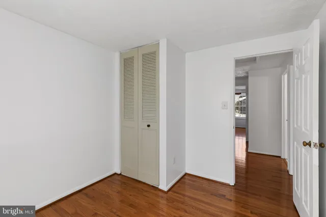 an empty room with wooden floor & closet area